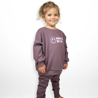 Child wearing oversized purple sweatshirt with 'Mama's Bestie' design, perfect for cozy adventures by My Mini Explorer. Handmade in Montana near Glacier National Park.