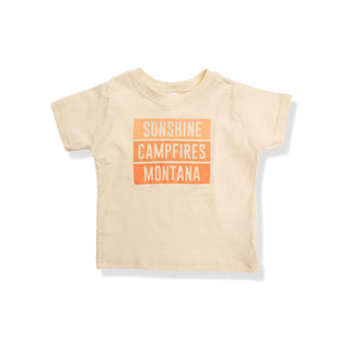 T-shirt in an off white color that has a graphic design saying "sunshine, campfires, Montana". 